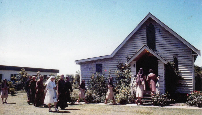 Members of the Abbey Community walking into the original timber Abbey Church.