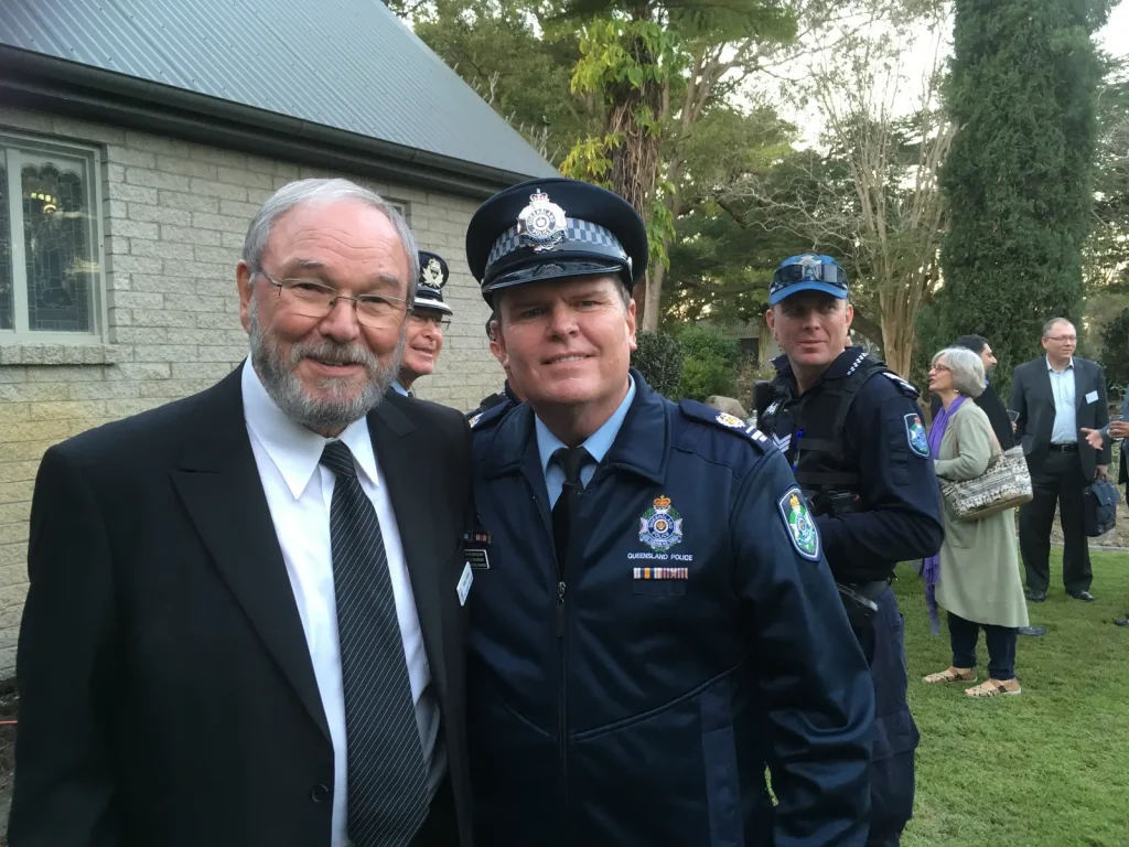 A guest with a senior Queensland Police Service officer at the Centre's 2018 interfaith launch, with more officers and guests on the lawn behind