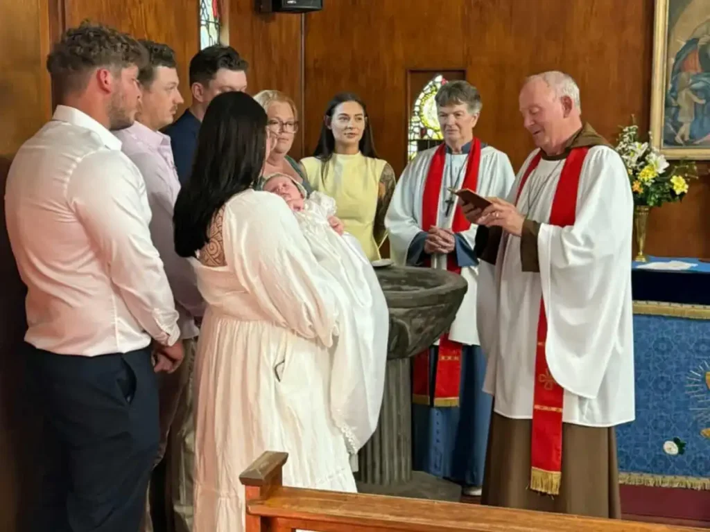 Infant Baptism at the Font Family gathered around the stone font as an infant is presented for baptism at The Abbey Church