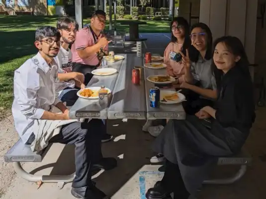 Forum participants sharing a meal at an outdoor picnic table at the Abbey Church in Caboolture